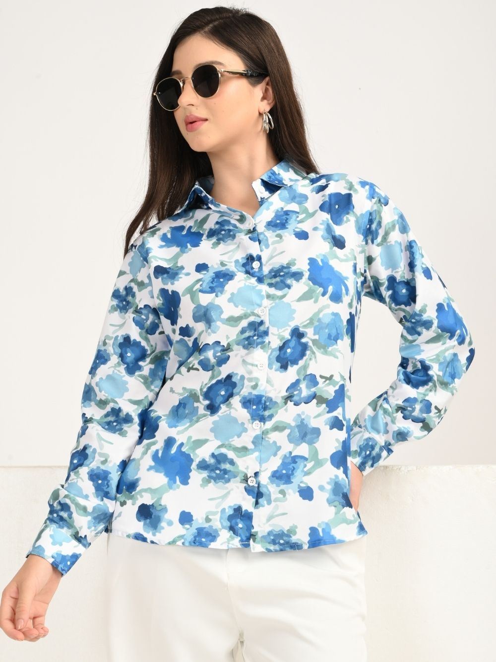Angled pose in blue floral shirt and white pants