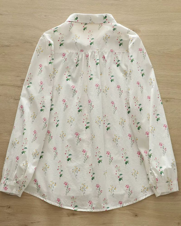 Back view of women's rayon shirt with pink and yellow floral print laid flat on wooden background

