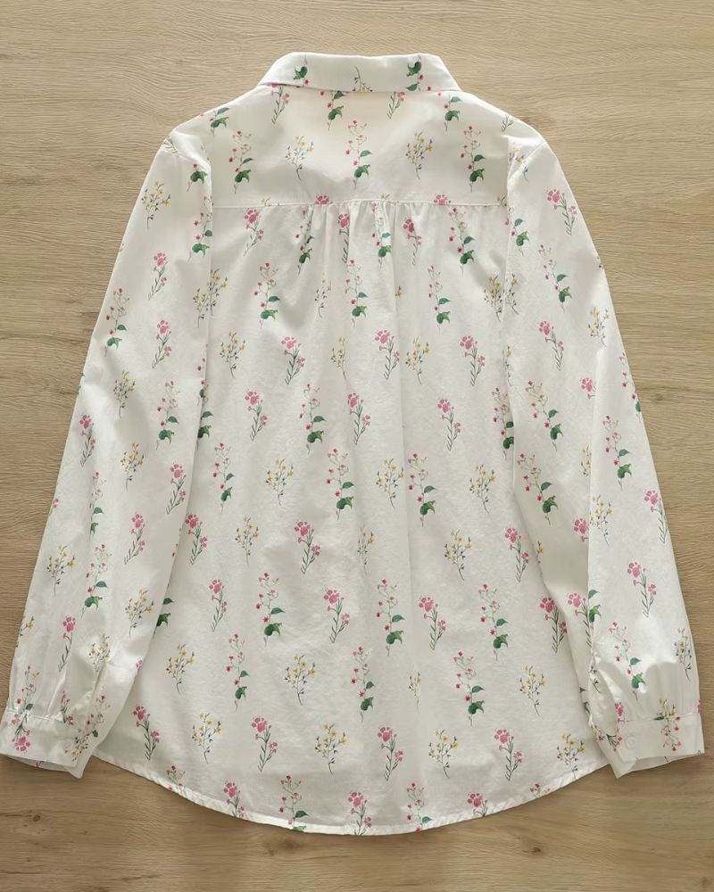 Back view of women's rayon shirt with pink and yellow floral print laid flat on wooden background

