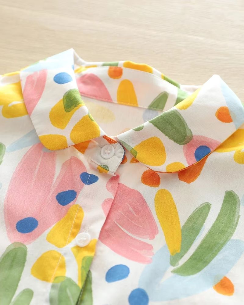 Detail of the shirt collar with multicolor watercolor print and top button closure

