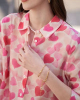 Detailed close-up of collar and buttons on pink heart printed blouse

