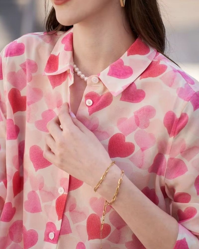 Detailed close-up of collar and buttons on pink heart printed blouse


