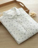 Folded Celeste Bloom rayon shirt with daisy floral print, styled on a wooden tray with soft natural lighting

