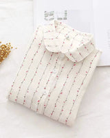 Folded white rayon shirt with pink floral vine print and buttons, styled on soft fabric

