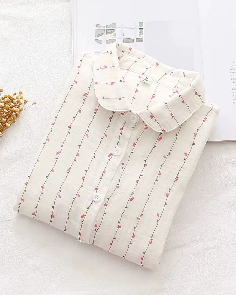Folded white rayon shirt with pink floral vine print and buttons, styled on soft fabric

