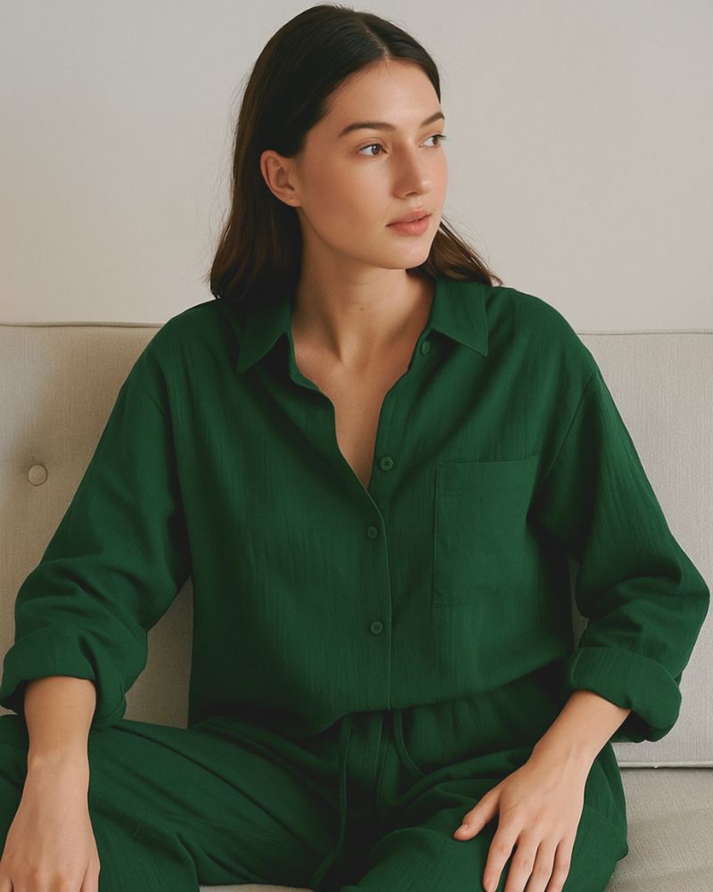 Woman seated in pure cotton forest green loungewear set on neutral couch



