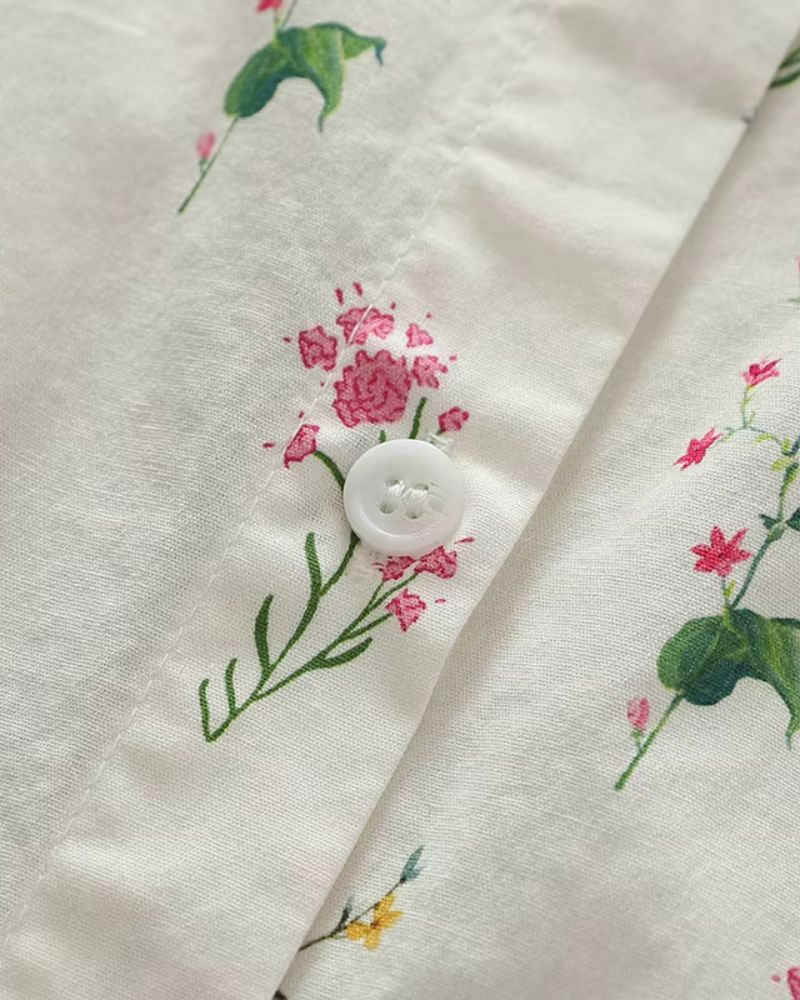 Macro image of a white button and pink flower print on soft ivory rayon shirt, showing fabric texture and finish

