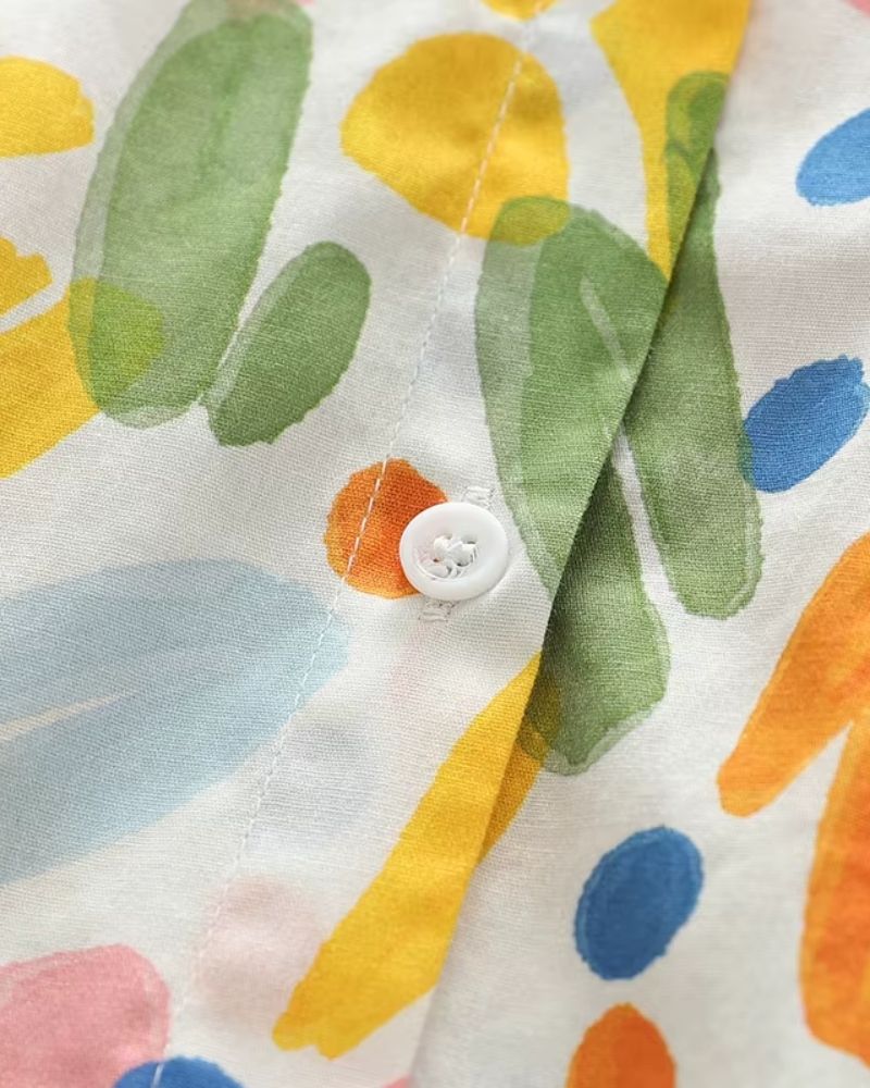 Macro shot of white button and vivid watercolor brushstroke print on rayon fabric

