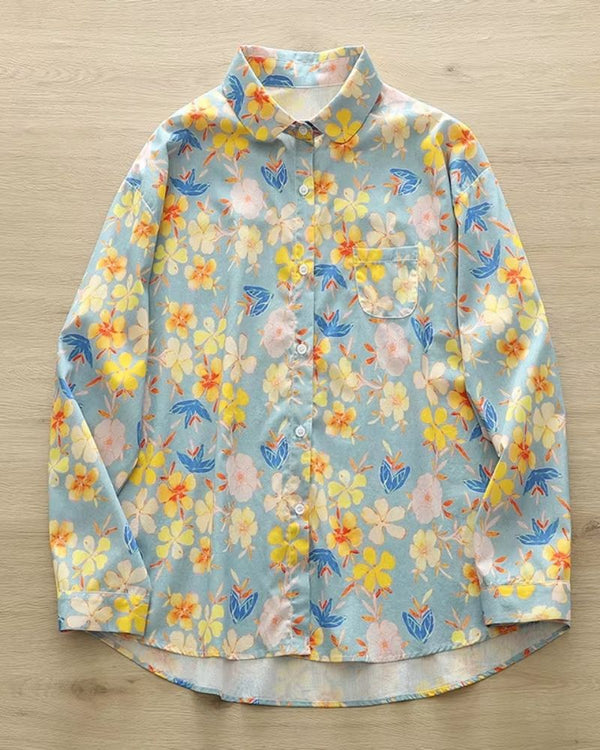 Sky blue rayon shirt with bright floral print in yellow, coral, and white on wooden background

