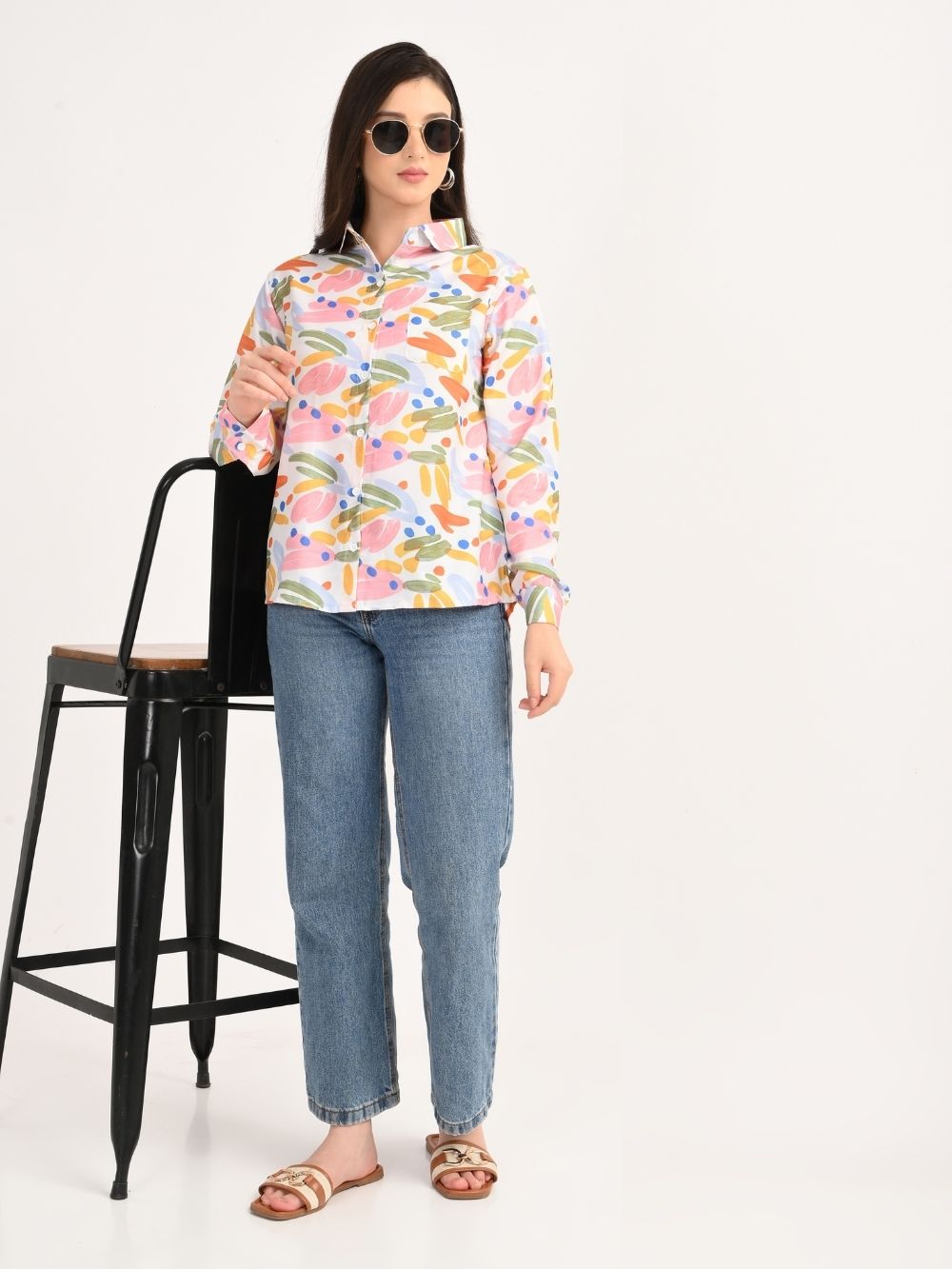 Woman wearing multicolor abstract print shirt with blue jeans and sunglasses